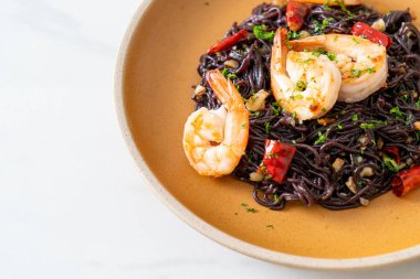 Sarımsaklı ve karidesli kızarmış siyah spagetti.