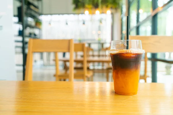 iced black coffee with orange yuzu juice cup on table in coffee shop cafe