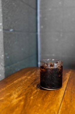Ahşap masada buzlu kola bardağı var.