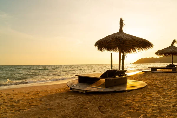 Stock image beach chair and umbrella with sea beach background at sunset time - Holidays and vacation concept