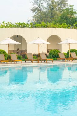 Okyanus geçmişi olan yüzme havuzunun etrafında havuzu olan şemsiyeler - tatil ve tatil kavramı