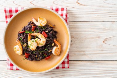 Sarımsaklı ve karidesli kızarmış siyah spagetti.