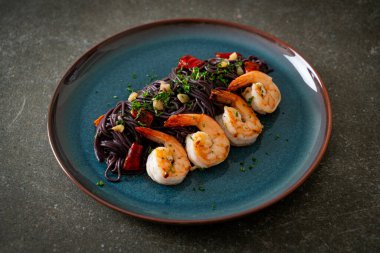 Sarımsaklı ve karidesli kızarmış siyah spagetti.