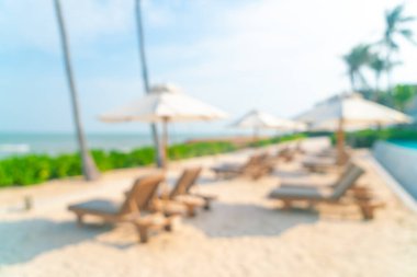 Arka planda plaj sandalyesi ve okyanus denizi olan soyut bulanık şemsiye