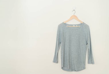 grey t-shirt hanging with wood hanger on wall
