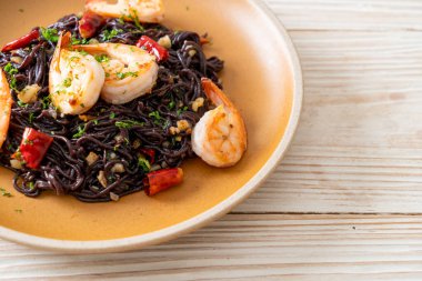 Sarımsaklı ve karidesli kızarmış siyah spagetti.