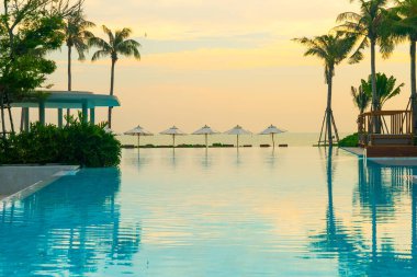 Okyanus geçmişi olan yüzme havuzunun etrafında havuzu olan şemsiyeler - tatil ve tatil kavramı