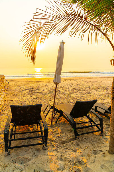 umbrella chair beach with palm tree and sea beach at sunrise times - vacation and holiday concept