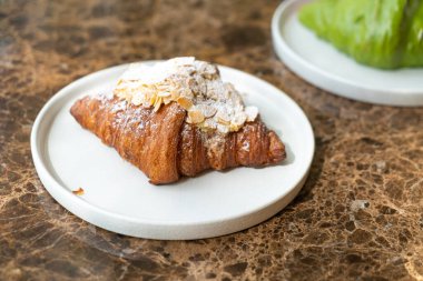 Beyaz tabakta taze badem kremalı kruvasan.