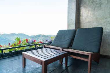 Dağ tepesi arka planında balkonda boş sandalye