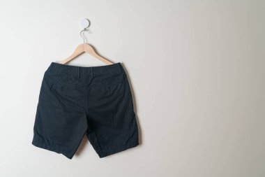 Kısa pantolon duvarda ahşap bir askıyla asılı.