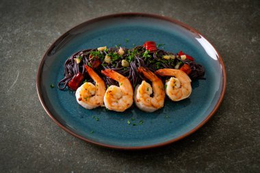 Sarımsaklı ve karidesli kızarmış siyah spagetti.