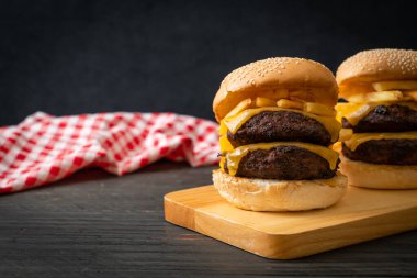 Peynirli ve patates kızartmalı hamburger veya sığır burger. Sağlıksız yemek tarzı.