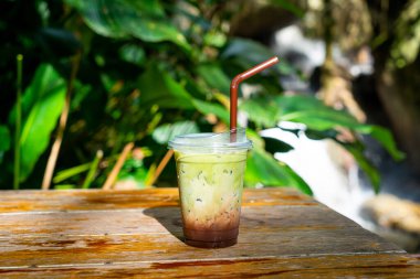 Buzlu yeşil çay, ahşap masadaki çikolatalı.