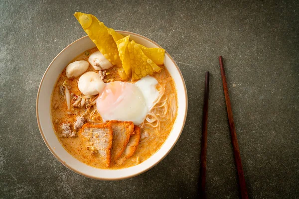 Rice vermicelli noodles with meatball, roasted pork and egg in spicy soup - Tom Yum Noodles