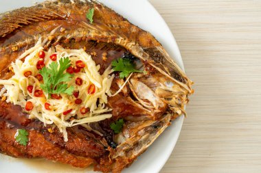 Balık soslu kızarmış deniz levreği balığı ve tabakta baharatlı salata.