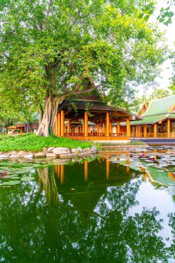Bahçede ağaç ve göl olan Tayland tarzında bir pavyon.