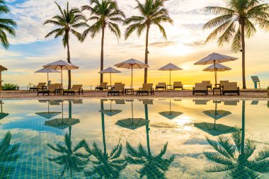 Şemsiye ve sandalye tatil ve tatil için dinlenme yeri otelinde yüzme havuzunda günbatımında veya gün doğumunda okyanus kıyısında