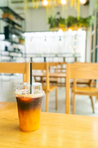 iced black coffee with orange yuzu juice cup on table in coffee shop cafe