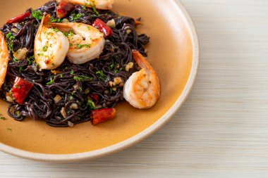 Sarımsaklı ve karidesli kızarmış siyah spagetti.