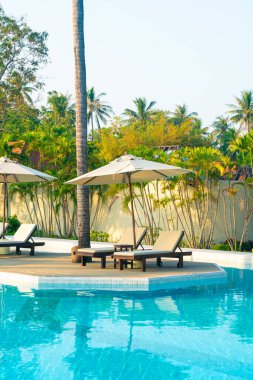 Okyanus geçmişi olan yüzme havuzunun etrafında havuzu olan şemsiyeler - tatil ve tatil kavramı