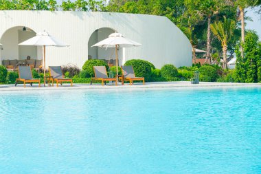 Okyanus geçmişi olan yüzme havuzunun etrafında havuzu olan şemsiyeler - tatil ve tatil kavramı