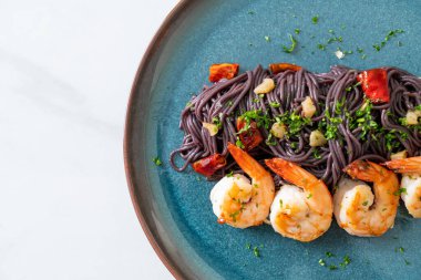Sarımsaklı ve karidesli kızarmış siyah spagetti.