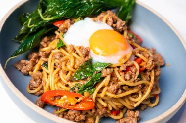 Baharatlı fesleğenli spagetti ve tabakta yumurta.