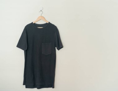 black t-shirt hanging with wood hanger on wall