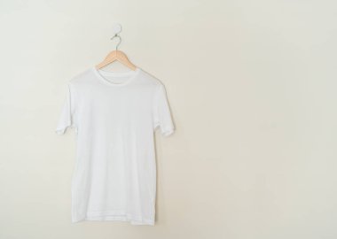 white t-shirt hanging with wood hanger on wall
