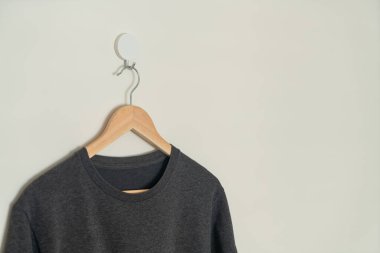 black t-shirt hanging with wood hanger on wall