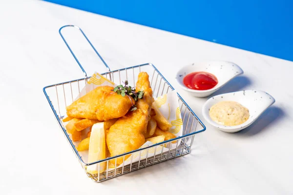 deep fried fish and chips in basket with sauce