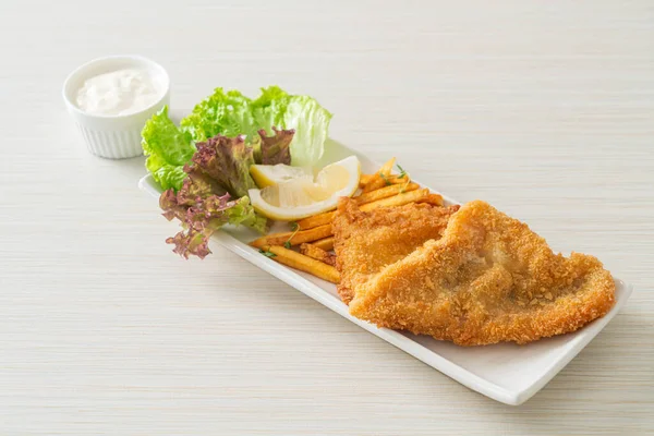 fish and chips - fried fish fillet with potatoes chips and lemon on white plate