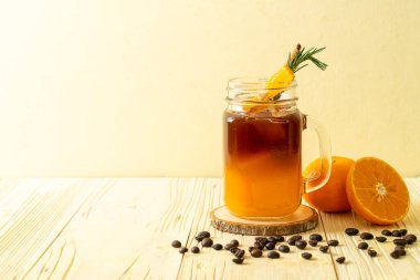 Bir bardak buzlu americano sade kahve ve biberiye ve tarçınla süslenmiş portakal ve limon suyu.