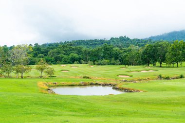 Green and Sand bunkers on Golf course with mountain hill background