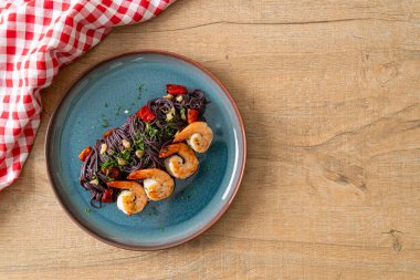 Sarımsaklı ve karidesli kızarmış siyah spagetti.