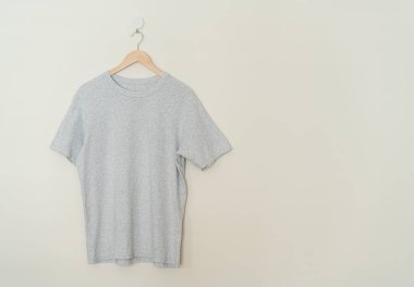 grey t-shirt hanging with wood hanger on wall