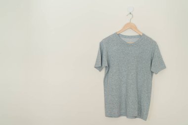grey t-shirt hanging with wood hanger on wall