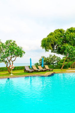 Sandalye havuzu ve şemsiyeyle okyanus arka planında yüzme havuzu