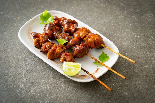 Stock image grilled chicken gizzard skewer with herbs and spices on plate