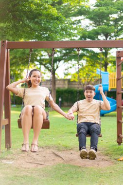 Asian couple love play on the swing in kids playground