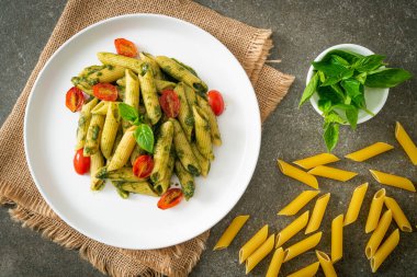 Pesto soslu ve domatesli makarna. Vejetaryen ve vejetaryen yemek tarzı.