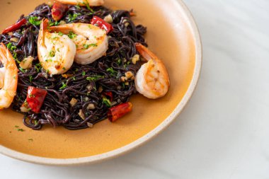 Sarımsaklı ve karidesli kızarmış siyah spagetti.