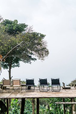 Dağ tepesi ve sisli arka planı olan balkonda boş bir sandalye.