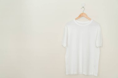 white t-shirt hanging with wood hanger on wall