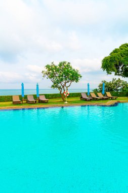 Sandalye havuzu ve şemsiyeyle okyanus arka planında yüzme havuzu