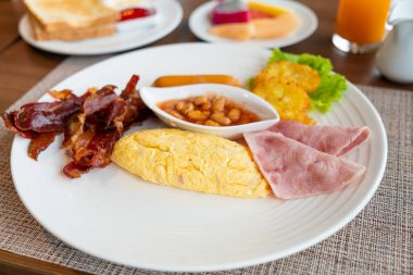 breakfast set - omelette, bacon, ham, sausages, fresh vegetable salad on plate in morning time - Hotel breakfast set concept