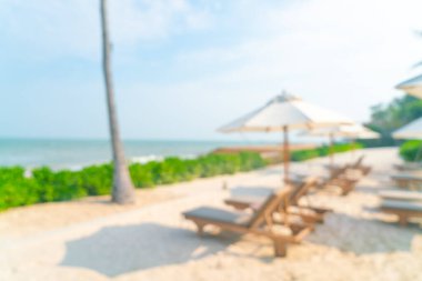 Arka planda plaj sandalyesi ve okyanus denizi olan soyut bulanık şemsiye