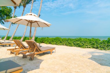 Plaj sandalyesi ve okyanus geçmişi olan şemsiye - tatil ve tatil kavramı