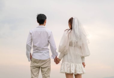 Happy young Asian couple in bride and groom clothing ready for marry and wedding celebrate